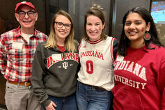 A small group of smiling Indiana University alumni gathered at a sporting event.